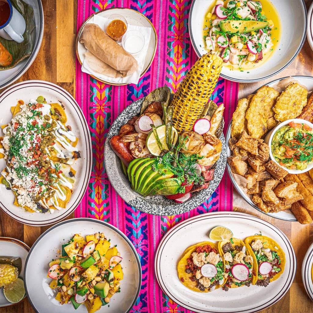 Guacamole, street corn, tacos and sides on a colorful table